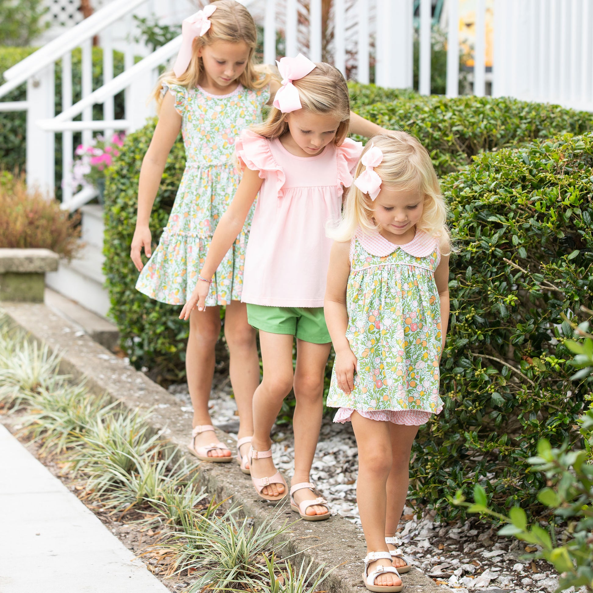 three little girls walking down a neighborhood sidewalk