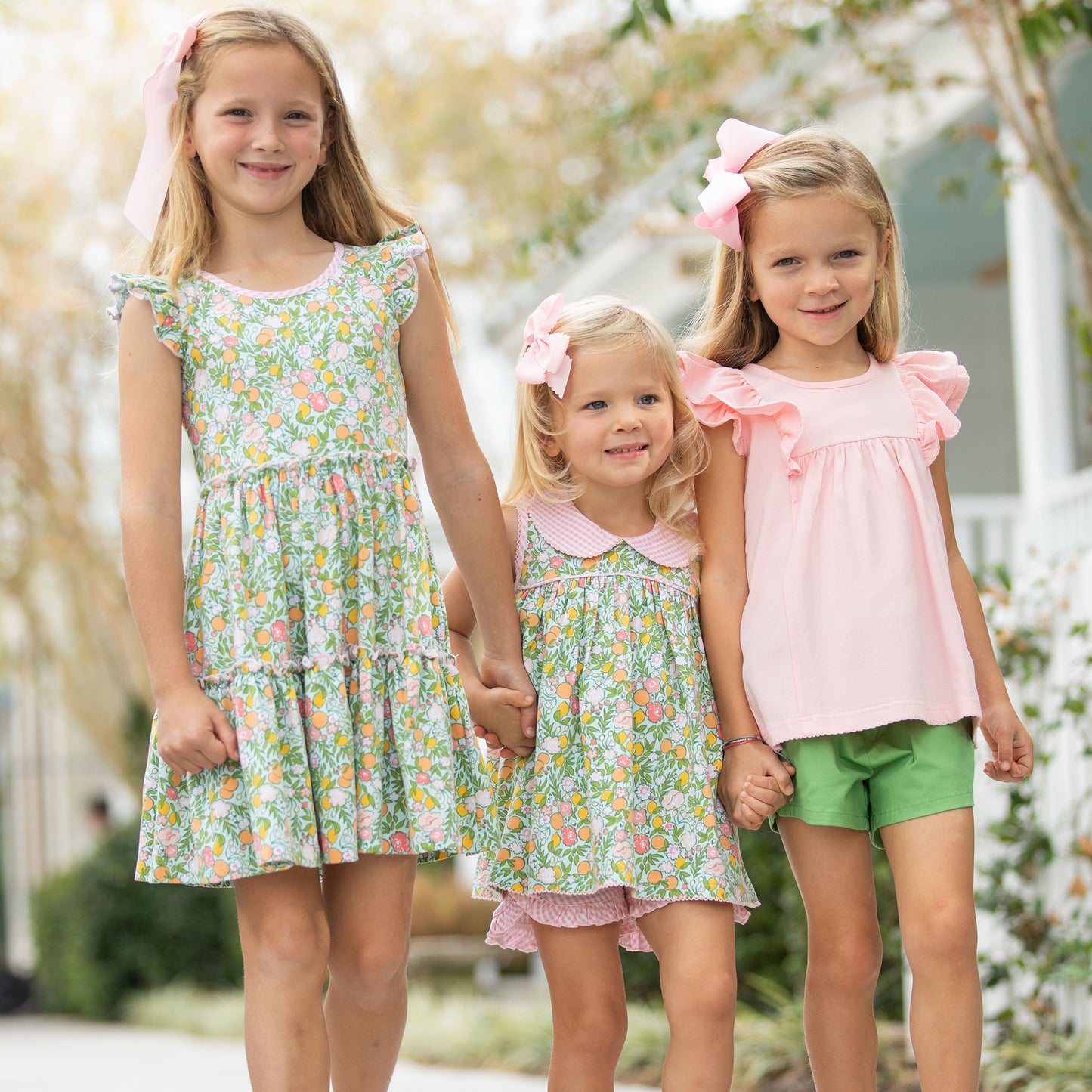 3 little girls smiling and walking hand in hand and one of them is wearing the Girl's Pink Swing Top