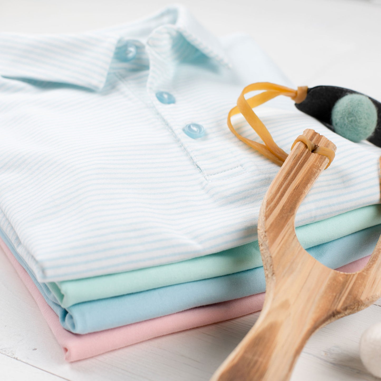 stack of knit polos with Briggs Blue Knit Polo on the top and a toy slingshot