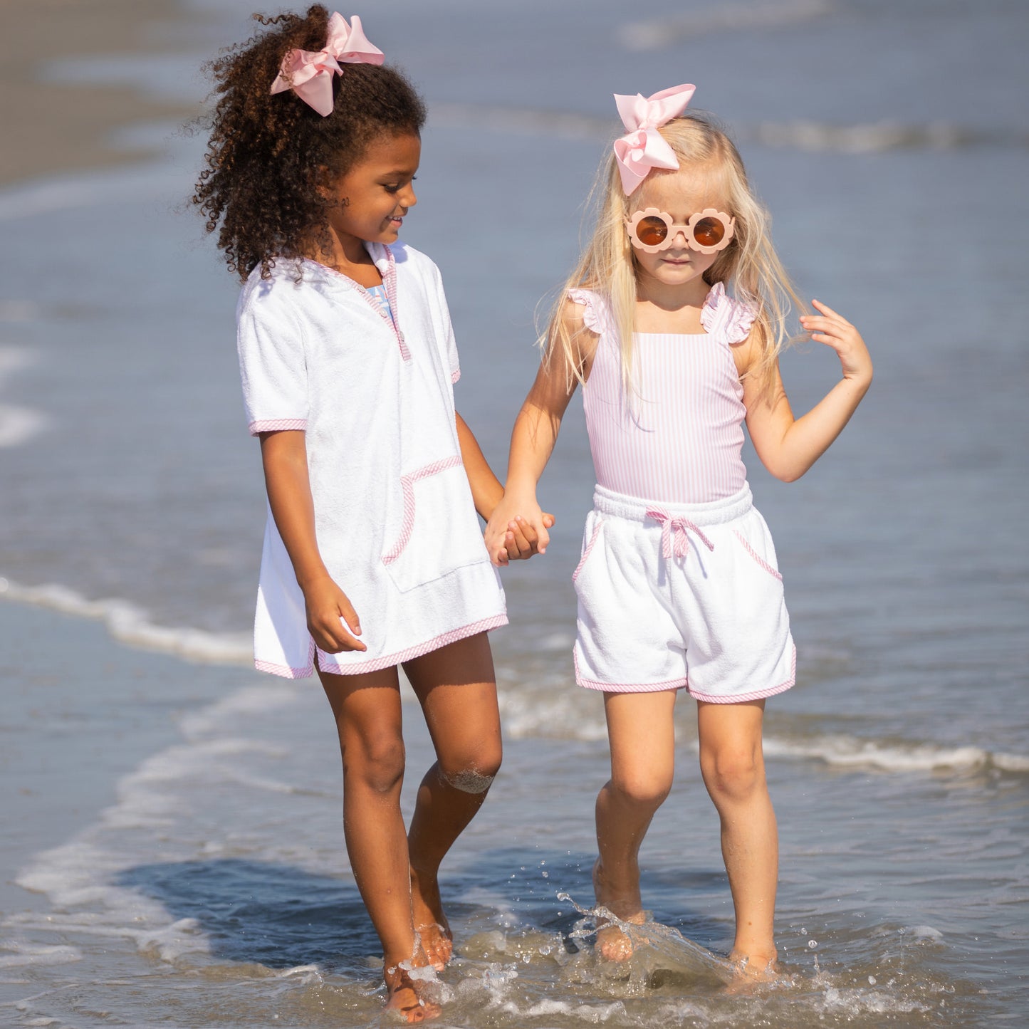 two little girls walking through the water at the beach