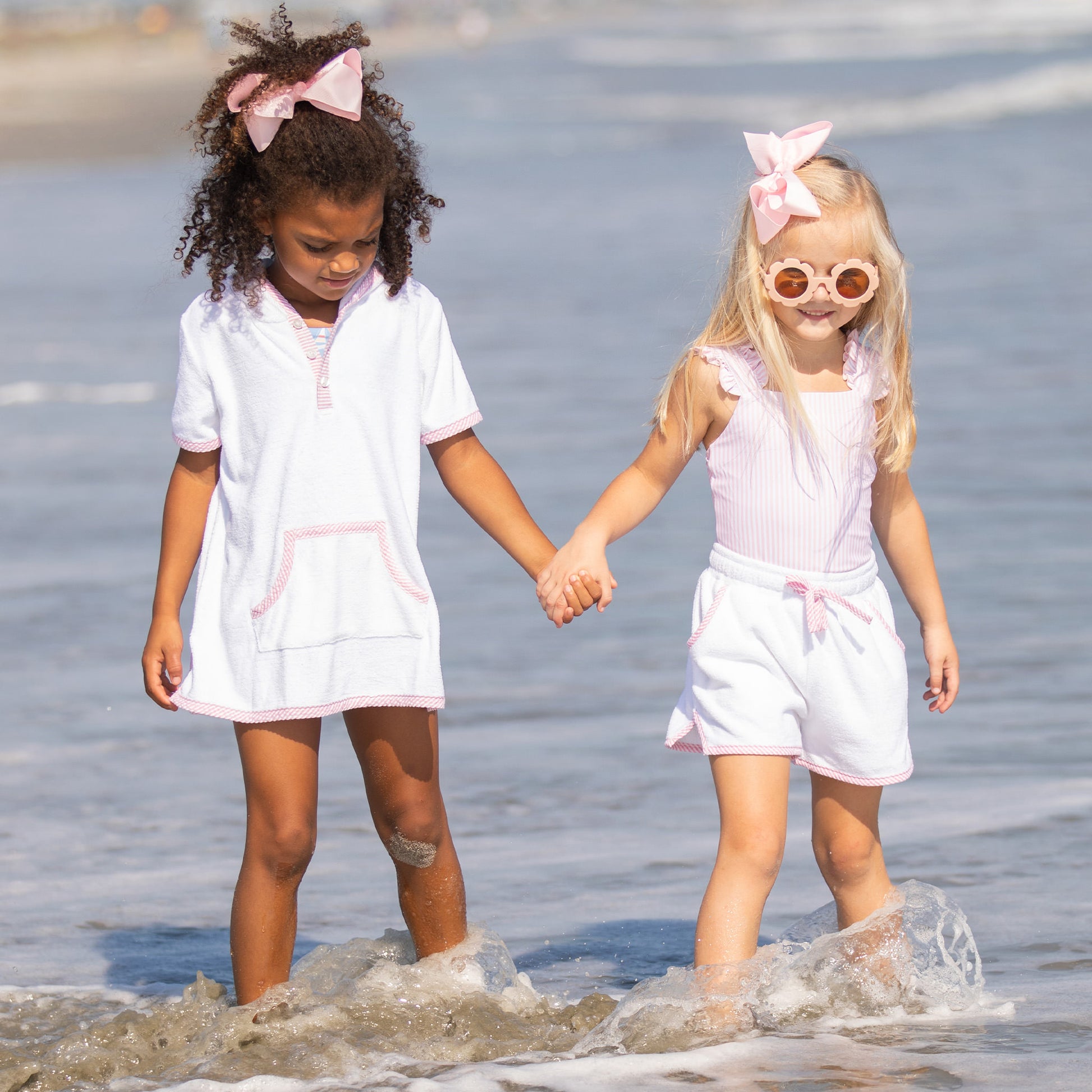 little girl wearing Brynn Beach Shorts holding hands with another little girl at the beach