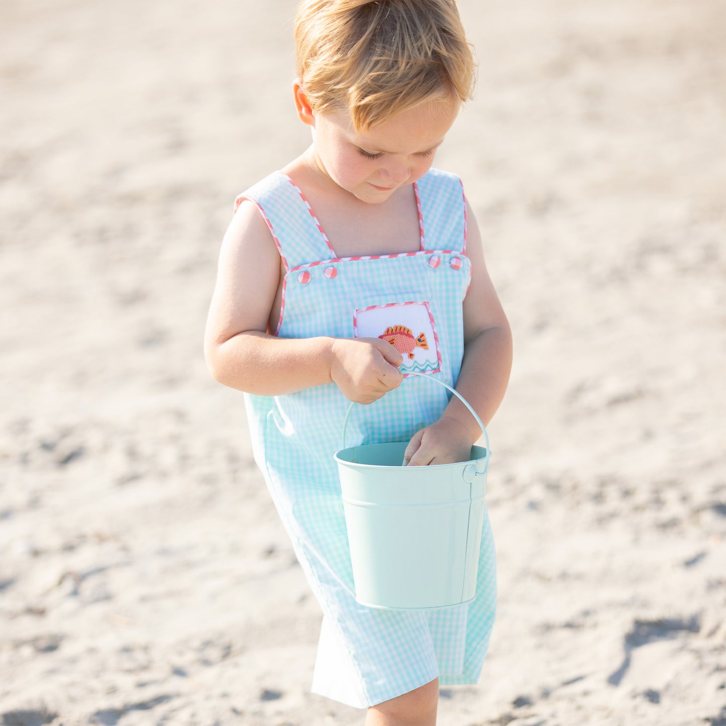 little boy with a beach bucket on the beach