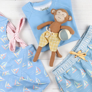flatlay of bathing suits and a monkey stuffed animal