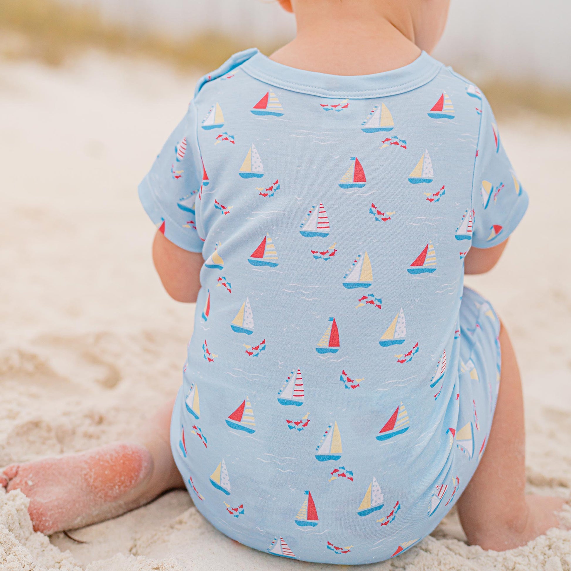 little boy sitting in the sand at the beach wearing Set Sail Romper