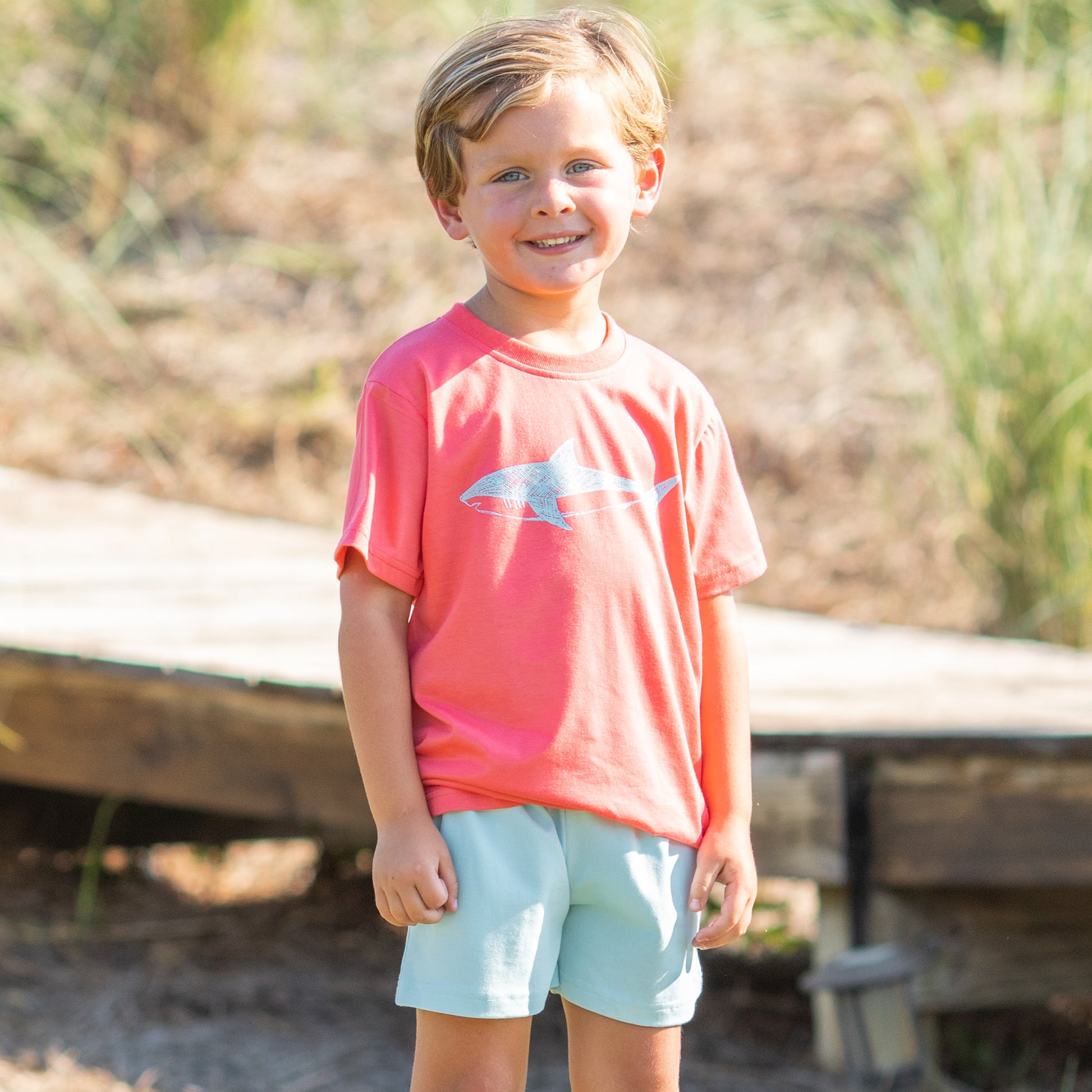 little boy wearing Great White Graphic Tee and light blue short on the beach