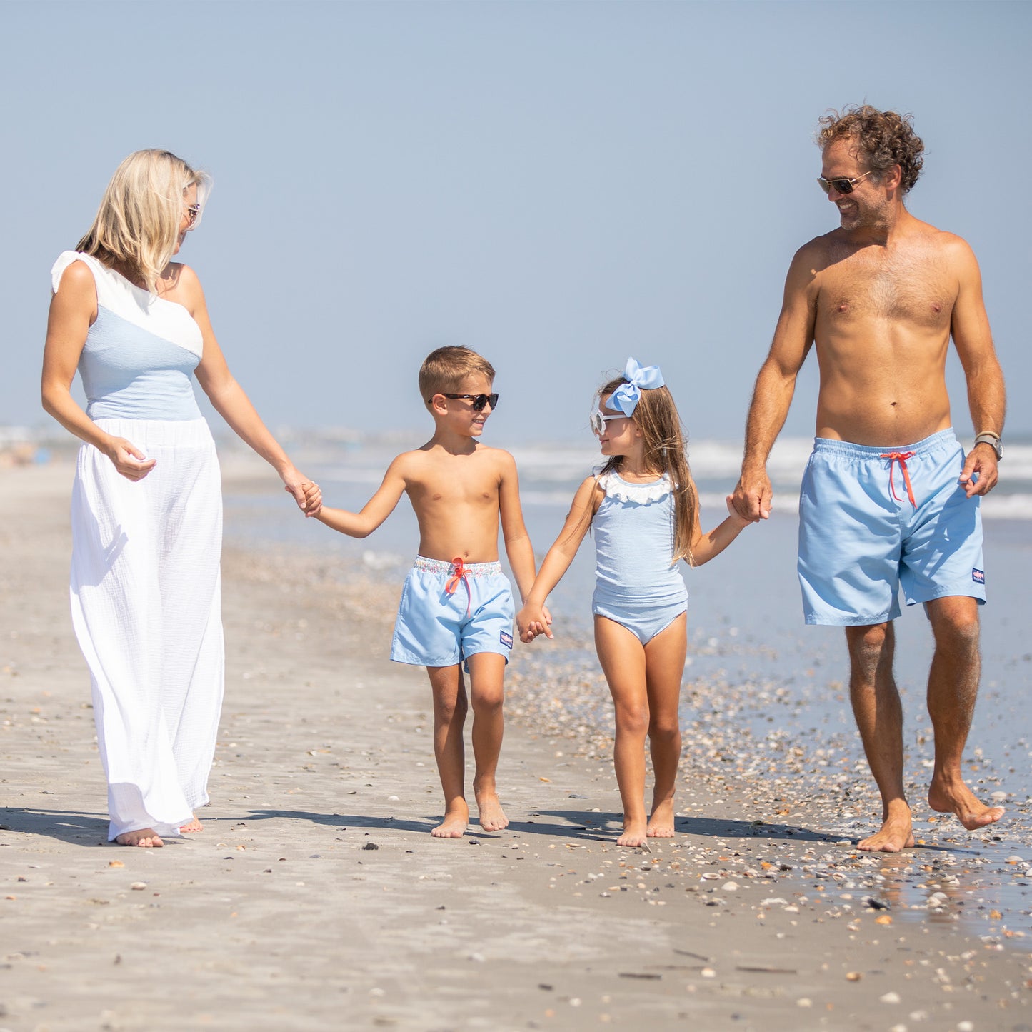 family walking on the beach in blue and white bathing suits