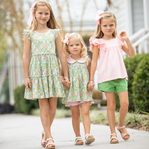 three little girls holding hands walking down the sidewalk