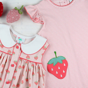 flatlay of a strawberry dress and pink and white striped shirt