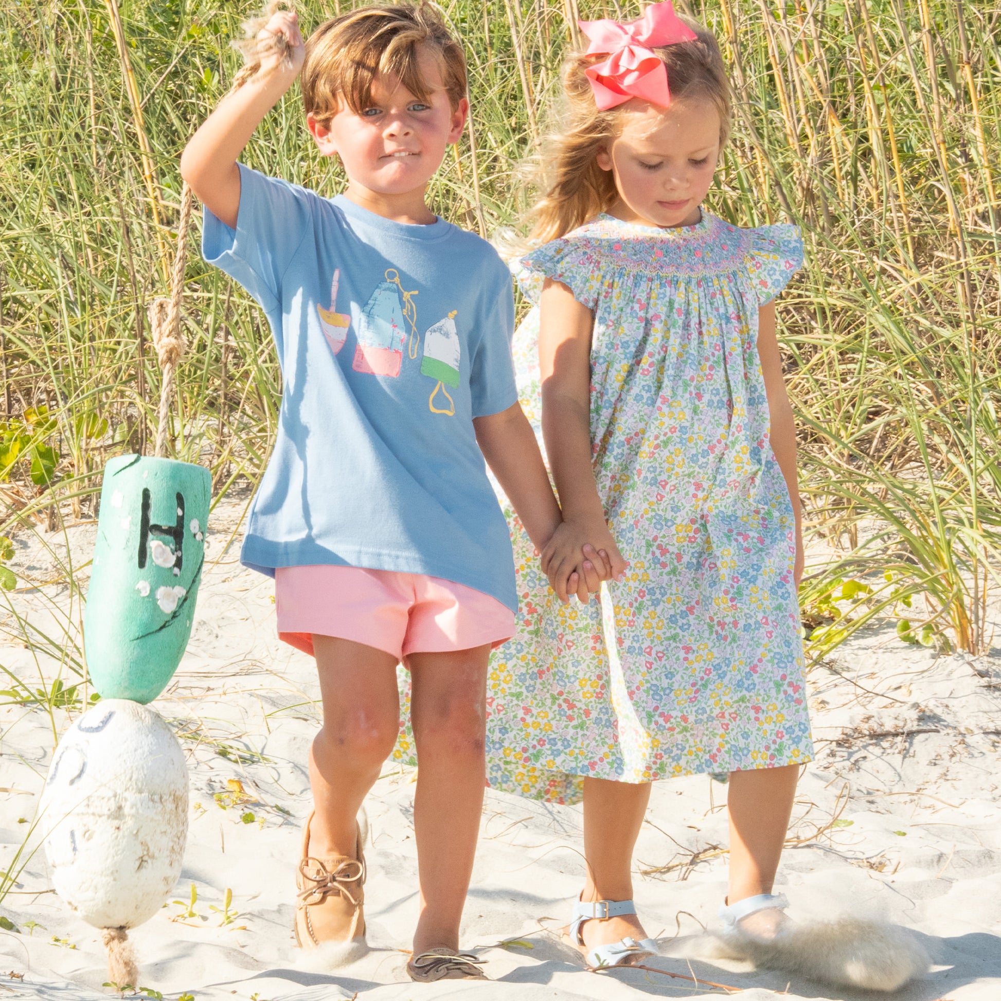 little bot and little girl holding hands walking down the beach