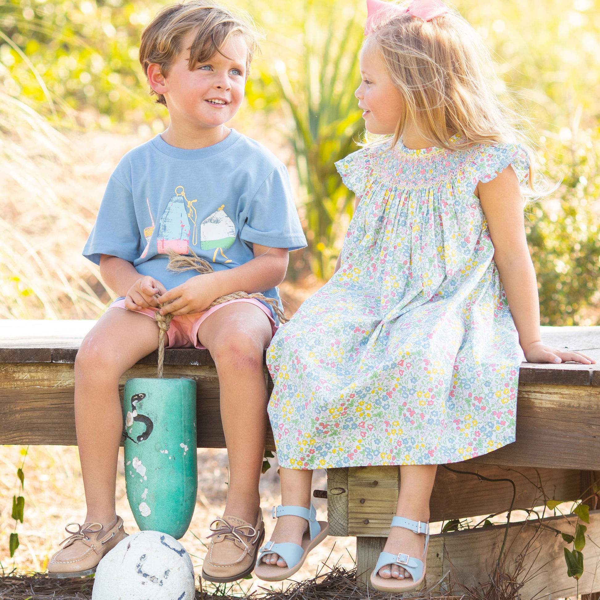 little boy and little girl sitting on the boardwalk at the beach