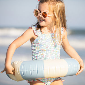 little girl in sunglass and blue floaty at the beach