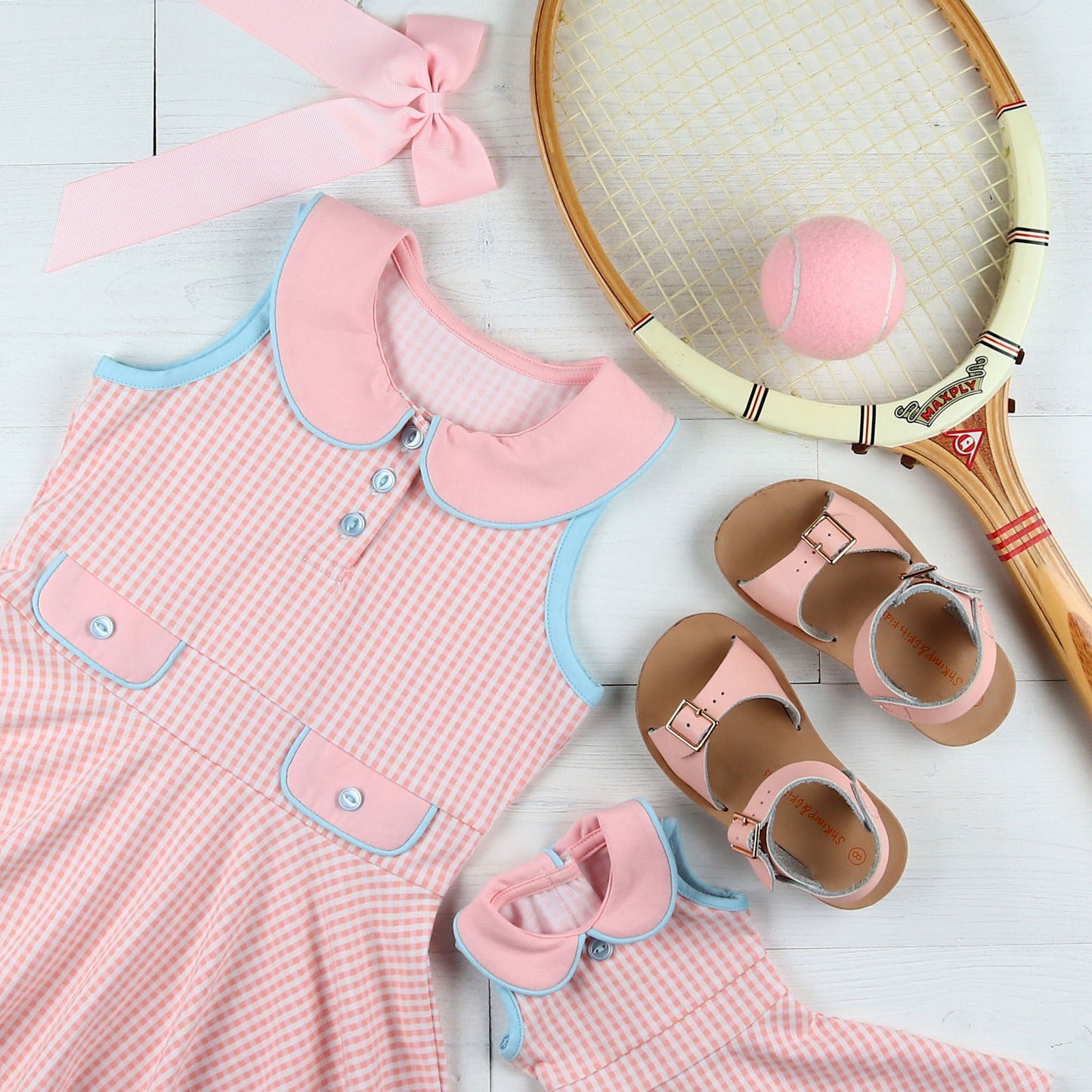 flatlay of Dress, tennis ball, tennis racket, pink bow,  sandals and matching doll dress