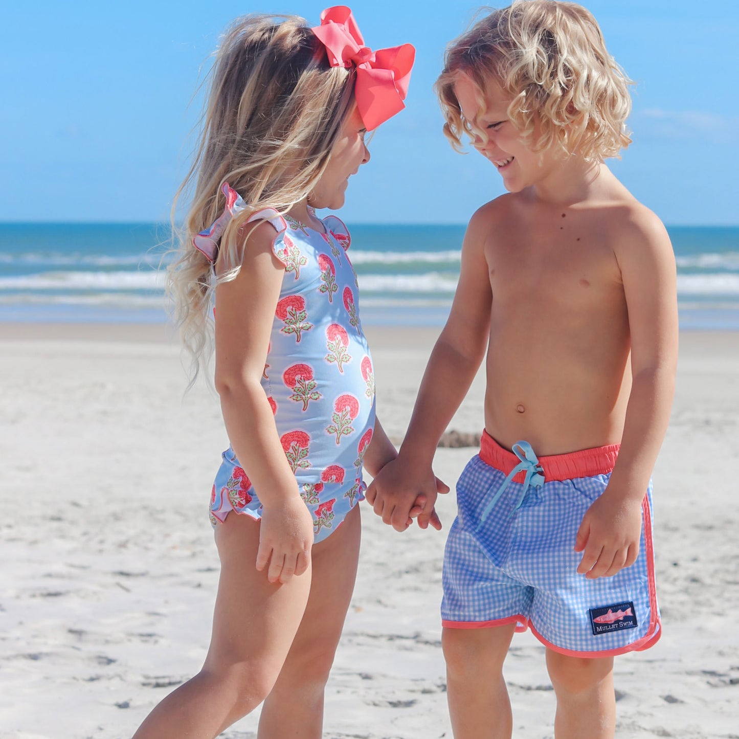 brother and sister holding hands on the beach