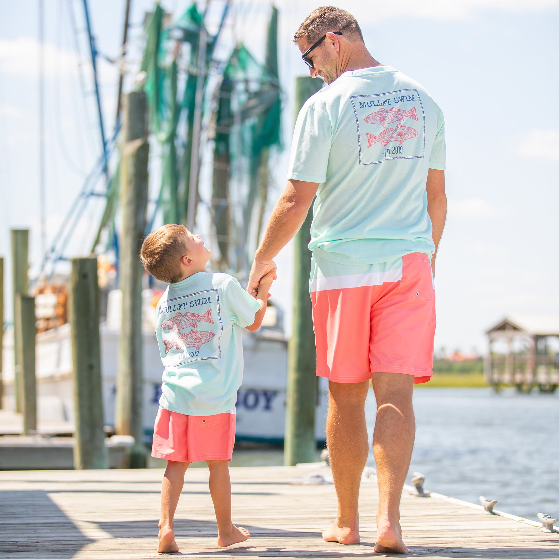 dad wearing Sorbet Swim Men's Boardshorts holding hands with his son on the boardwalk