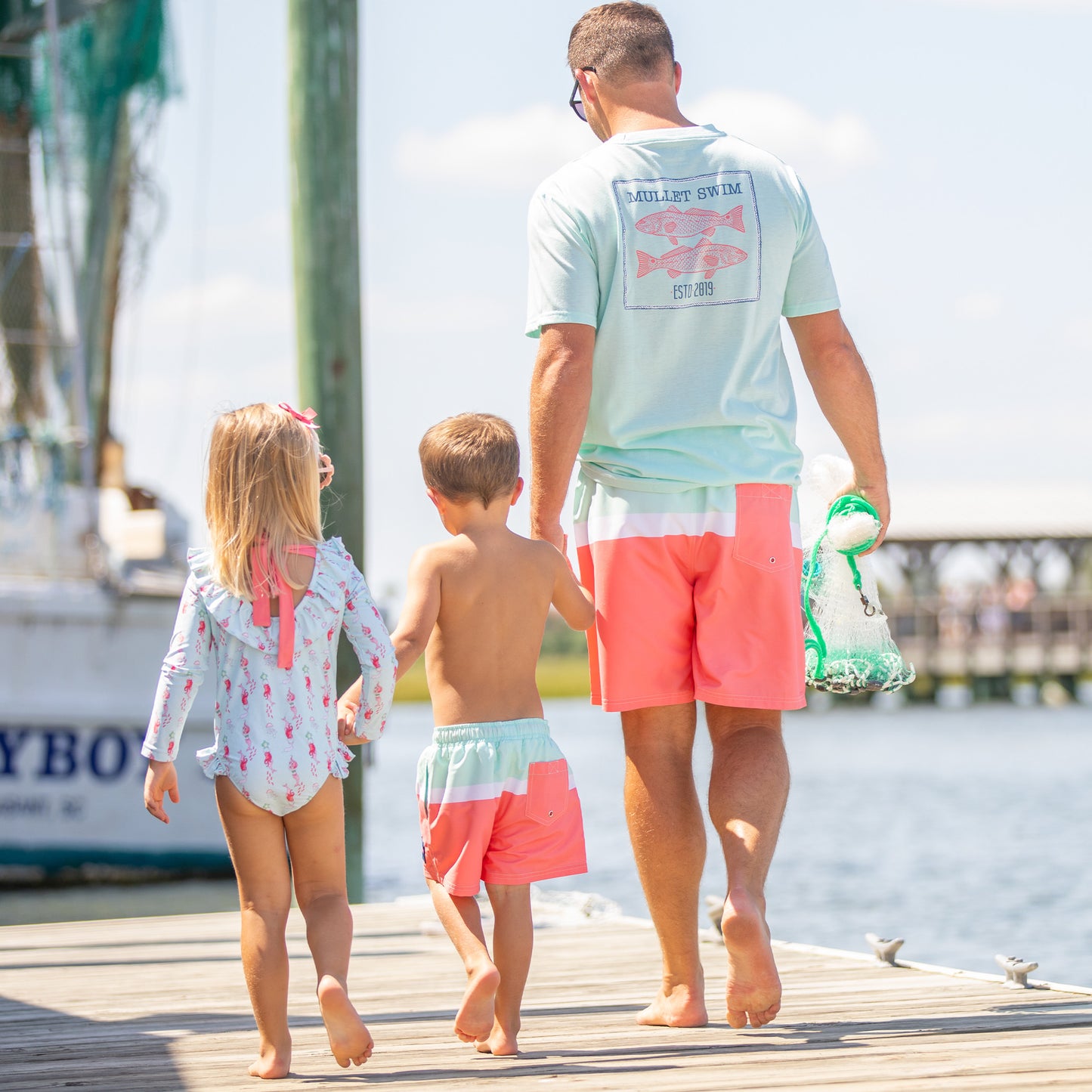 dad holding his son and daughters hand on the boardwalk