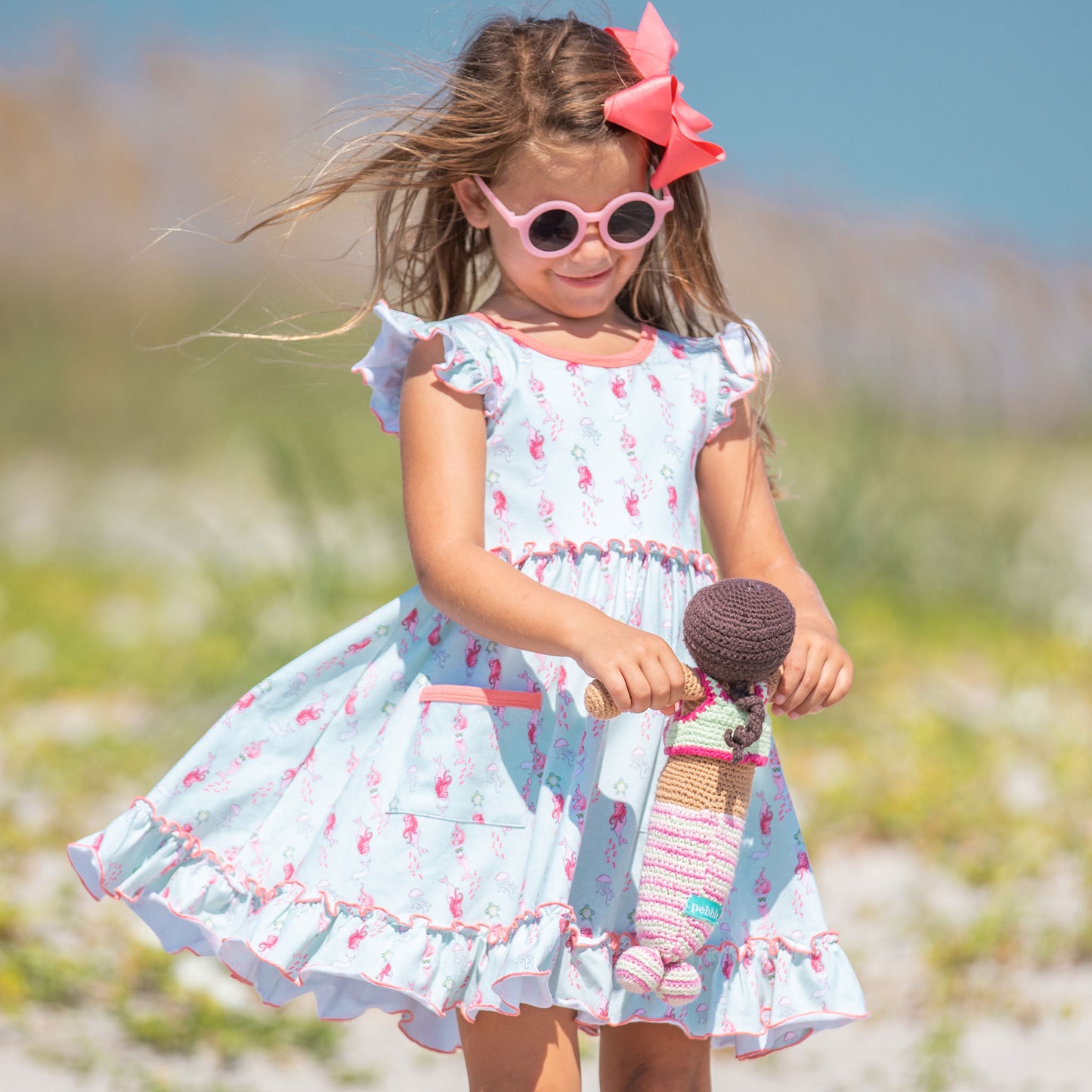 little girl in sunglasses and Under the Sea Twirl Dress playing at the beach